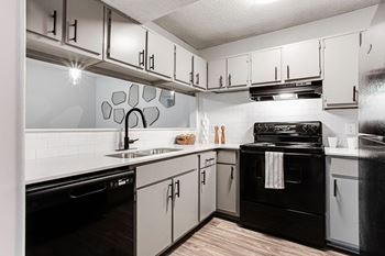 A modern kitchen with black appliances and white cabinets.at Laurel, Georgia  